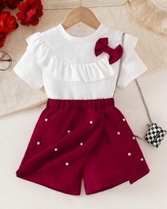 top de punto con volantes y lazo, falda corta con abertura y decoración de perlas